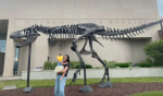 Natalie and her daughter in front of a fossil of a dinosaur.